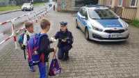 policjantka wręcza odblaski przed szkołą