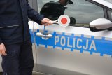 policjant z tarczą do zatrzymywania pojazdów na tle radiowozu