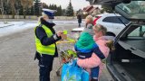 policjantka wręcza elementy odblaskowe rodzinie podczas akcji Bezpieczny pieszy