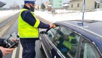 policjant wręcza pączka kierowcy