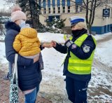policjantka wręcza odblaski kobiecie z dzieckiem