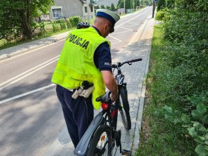 policjant ruchu drogowego sprawdza obowiązkowe wyposażenie roweru