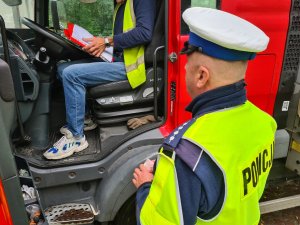 policjant kontroluje uprawnienia kierowcy samochodu ciężarowego