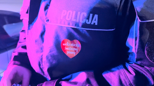 zdjęcie przedstawia zbliżenie na serduszko WOŚP naklejone na kurtce policjanta