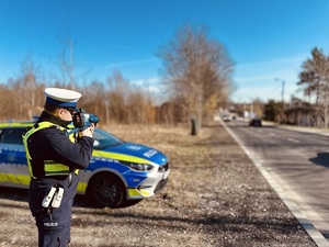zdjęcie przedstawia policjanta w trakcie kontroli prędkości pojazdów