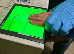 zdjęcie przedstawia zbliżenie na dłoń w trakcie pobierania odcisków palców
