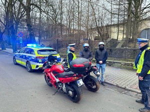 zdjęcie przedstawia radiowóz, dwa motocykle oraz policjantów i dwóch motocyklistów w trakcie kontroli drogowej
