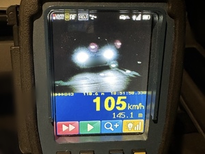 zdjęcie przedstawia ekran miernika prędkości na którym widać prędkość białego samochodu 105 km/h