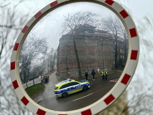 zdjęcie przedstawia radiowóz i policjantów widocznych w lustrze drogowym